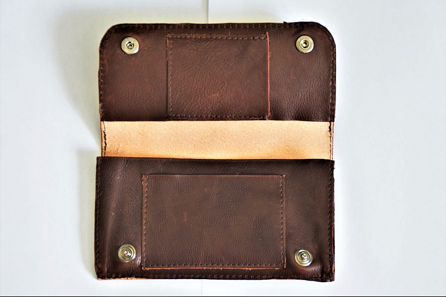 Portefeuille artisanal en cuir marron avec boutons-pression.